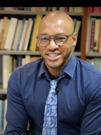 David Sterling Brown sits in front of bookcase